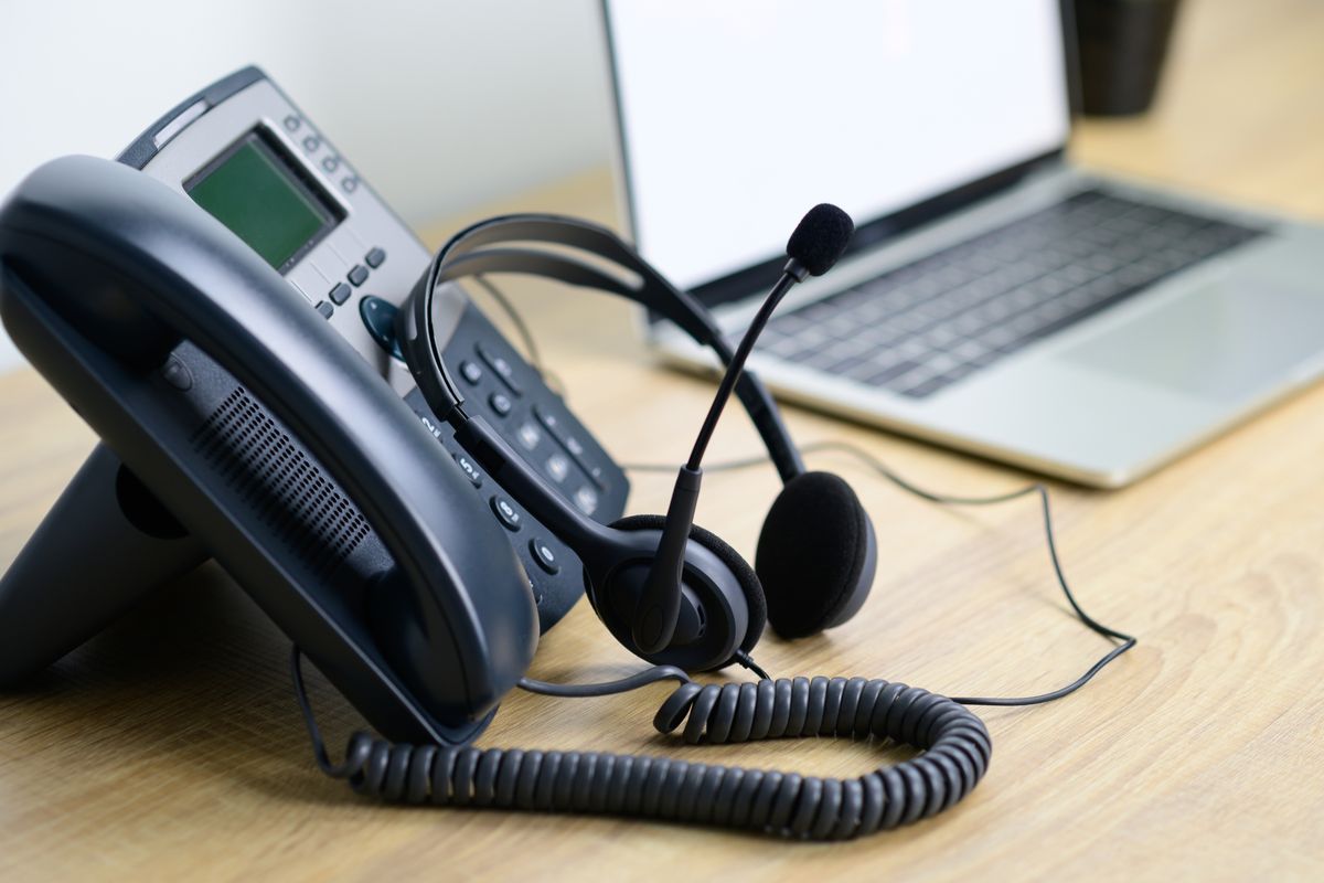 IP-Tischtelefon und Headset neben einem Laptop auf dem Schreibtisch