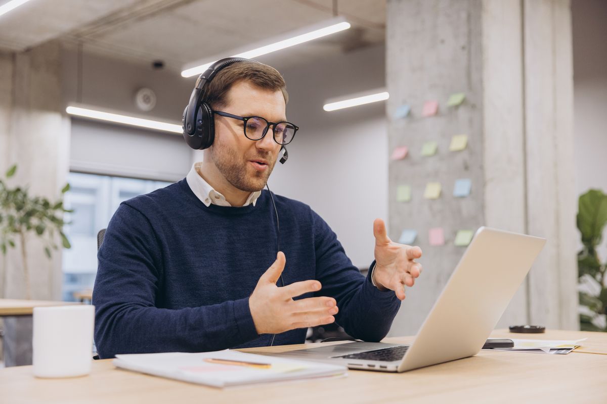 IT-Berater mit Headset erklärt im Videogespräch am Laptop