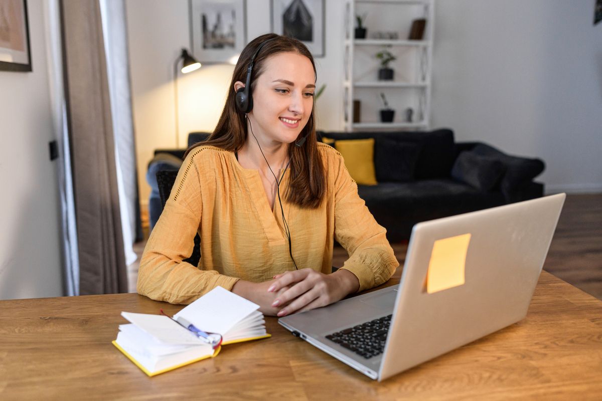 Teilnehmerin mit Headset folgt einer Online-Schulung am Laptop